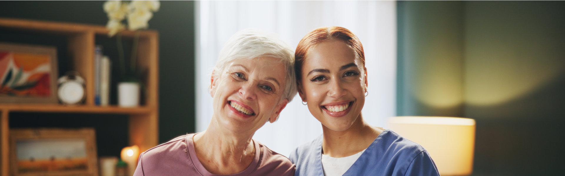 Two smiling women are posed indoors